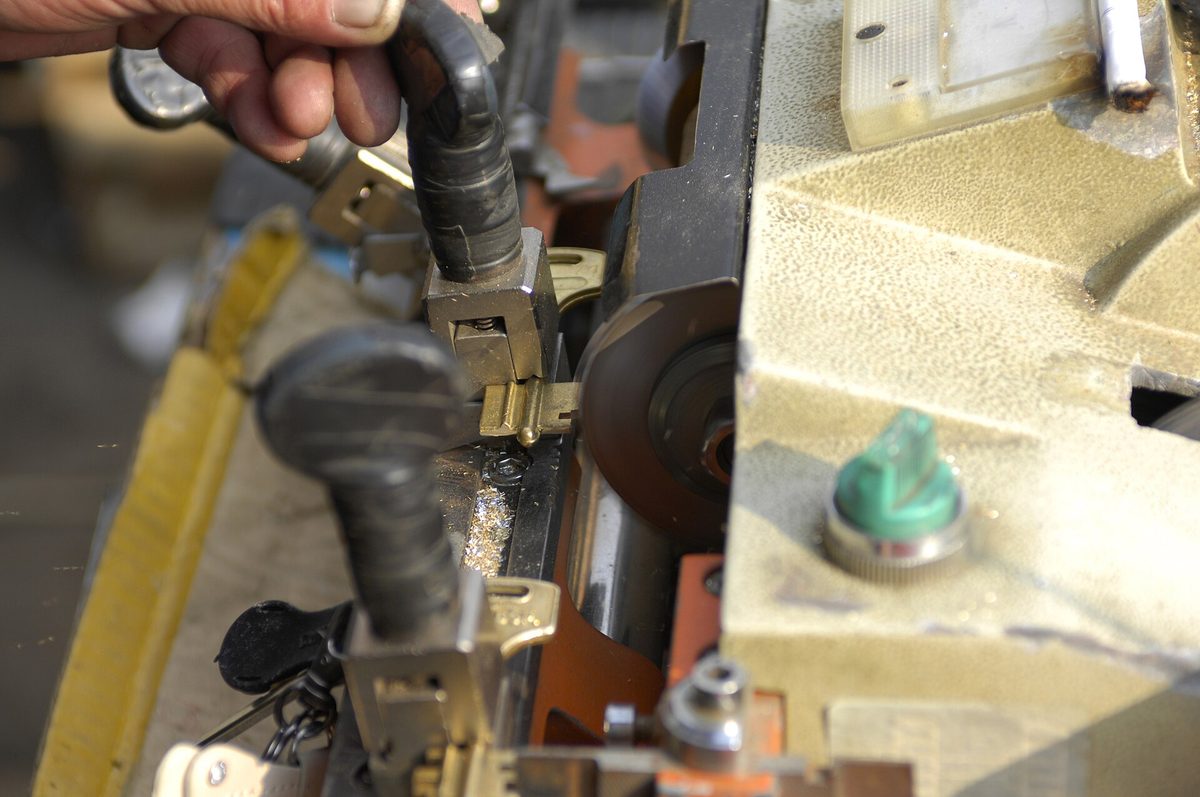 Cerrajero guiando una llave en una duplicadora manual con fresa de disco